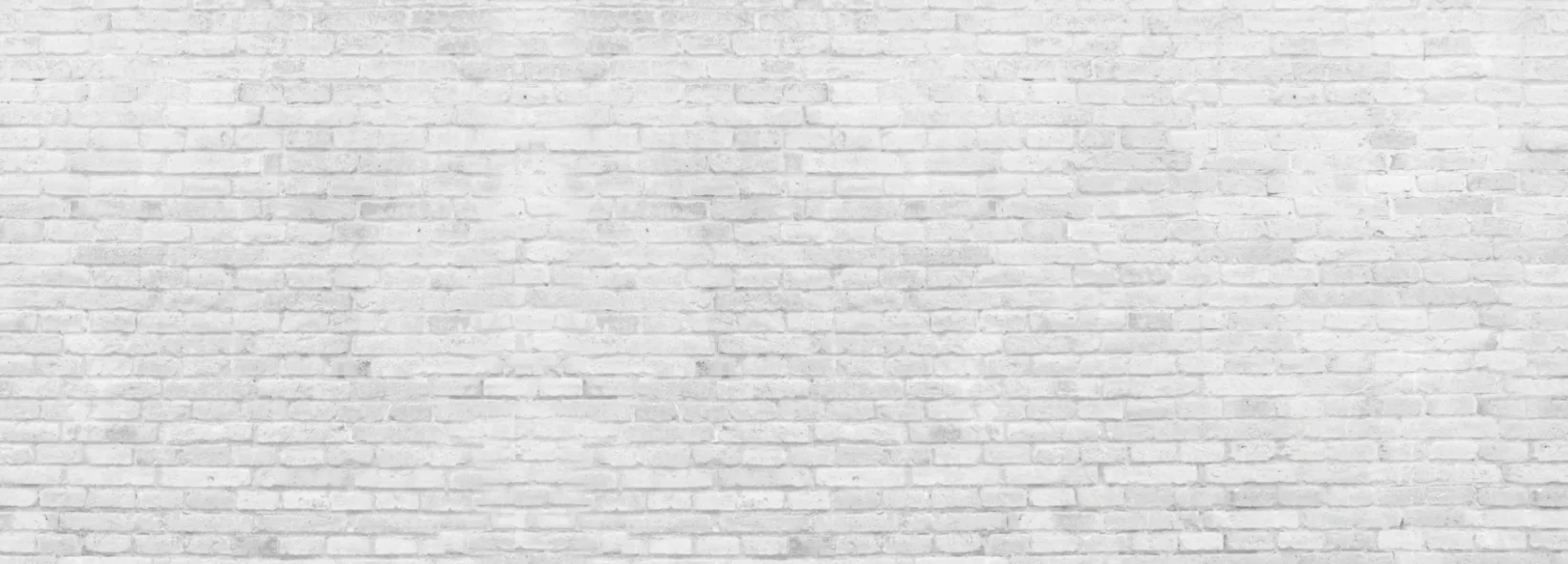 Weiße Ziegelsteinmauer mit gleichmäßig angeordneten Steinen.